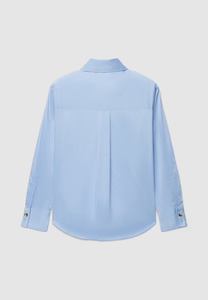 Camicia a maniche lunghe azzurro chiaro con texture morbida, colletto strutturato, piega posteriore e polsini con bottoni.