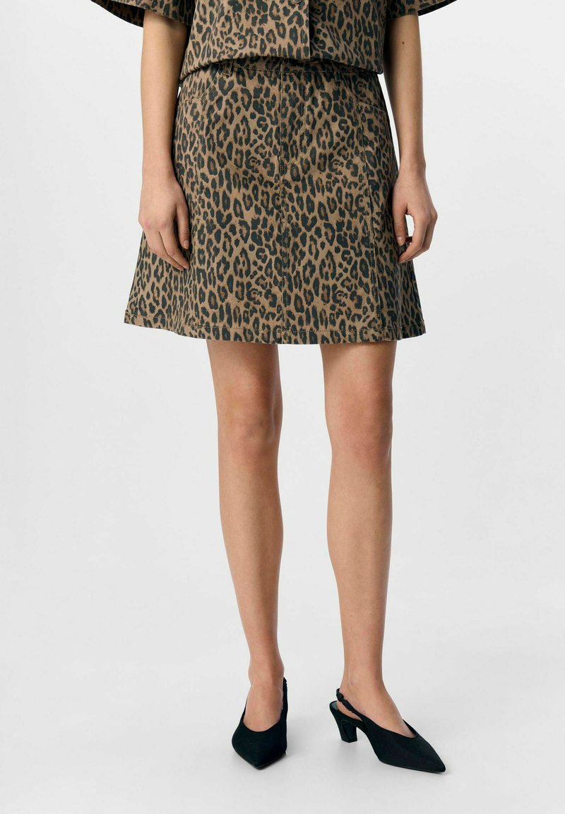 Djurtryckkjol i brunt och svart, med en utvändig design och slät yta. Matchad med svarta, spetsiga slingbacks.