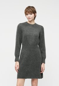 Vestido cinza de malha com decote redondo, mangas longas e corpete justo. Textura suave e padrão canelado discreto por todo o vestido.