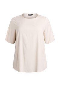 Jasnobeżowa koszulka z miękkiego materiału, z okrągłym dekoltem, krótkimi rękawami i luźnym krojem. Minimalistyczny design bez wzorów.