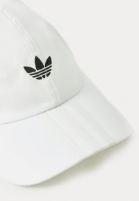 Hvid baseballcap med en buet skygge, lavet af glat stof. Har et sort logo med tre striber på fronten og striber langs siderne.