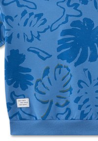 Blue sweatshirt featuring a botanical print with large leaf patterns in darker blue and green. Includes a white label at the bottom.