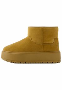 Yellow suede ankle boot with a flat, textured sole. Features a rounded toe and a stitched side panel. Soft lining visible at the top.