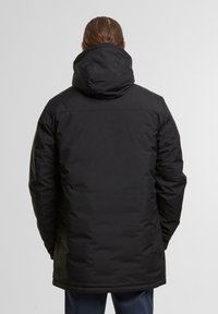 Jachetă izolată neagră cu glugă, având un exterior neted, mâneci lungi și o croială până la șold. Design minimalistic fără logo-uri vizibile.