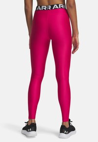 Enganliegende Sportleggings in lebhaftem Pink, hergestellt aus einem glatten, dehnbaren Stoff. Mit einem schwarzen, gebrandeten Bund und schmal zulaufenden Beinen.