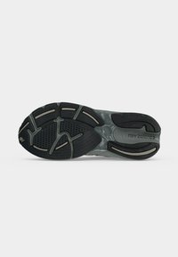 Μαύρη και γκρι σόλα αθλητικού παπουτσιού New Balance με υφή σε σχήμα πέλματος και το όνομα της μάρκας στην περιοχή της φτέρνας.