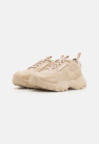 Beiga sportskor med texturerad mesh och syntetiskt överdrag, utrustade med snören, en dragflik och en klumpig sula av gummi.