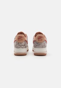 Nike Air sneakers featuring a textured snake-print design in light gray, with coral accents, padded collar, and a rubber outsole.