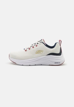 Baskets blanches de sport avec tige en mesh, accents bleu marine et rouge, semelle blanche rembourrée étiquetée "VAPORFOAM," et lacets traditionnels.