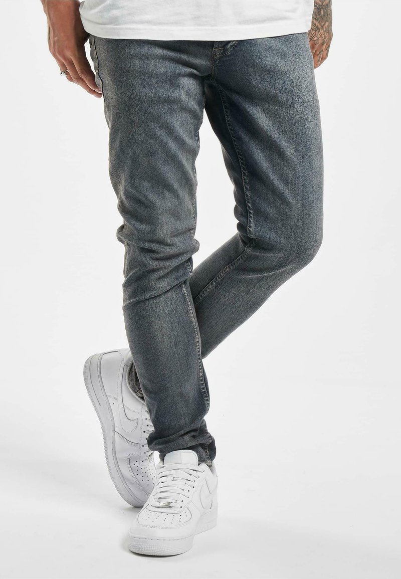 Jeans in denim grigio con una vestibilità slim, leggermente sbiaditi e design classico a 5 tasche. Abbinati a sneakers bianche e una t-shirt bianca semplice.