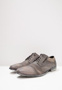 Chaussures en cuir marron avec accents texturés, finition lisse, bout arrondi, design à lacets et panneau en tissu contrastant au talon.