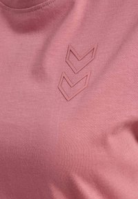 Lyserød bomulds-t-shirt med tre forhøjede, overlappende chevronformer i en lidt mørkere lyserød, med en glat tekstur og rund halsudskæring.