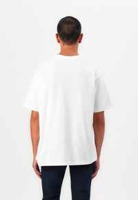 Weißes Baumwoll-T-Shirt mit entspannter Passform, kurzen Ärmeln und Rundhalsausschnitt; zeichnet sich durch ein schlichtes Design ohne sichtbare Muster oder Akzente aus.