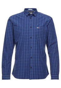 Koszula na długi rękaw z ciemnoniebieskiego materiału w kratkę. Posiada kieszeń na piersi oraz metkę z logo na kieszeni.