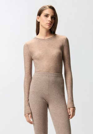 Maglietta lunga color marrone chiaro in materiale traslucido con dettagli scintillanti sottili, abbinata a leggings a coste, a vita alta, marrone chiaro.