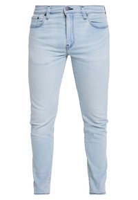 Světle modré džíny s slim fit střihem, které mají standardní pás, kovové zapínání na knoflík a přední a zadní kapsy.