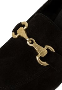 Černé semišové mokasíny s detailním zlatým kováním ve tvaru ohlávky. Hladký, zaoblený tvar s jemným povrchem a minimalistickým designem.