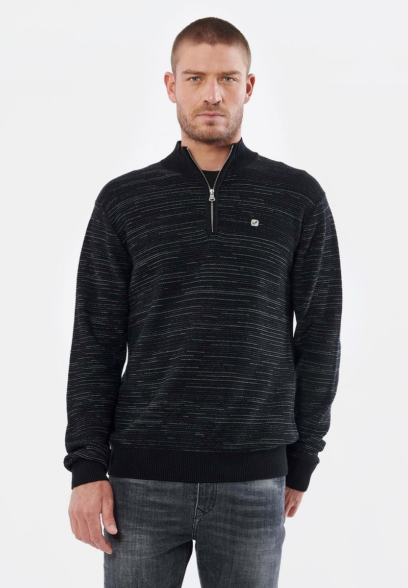 Sweat à zip noir présentant un motif texturé avec des rayures horizontales, accompagné de poignets et d'un ourlet côtelés, ainsi qu'un petit logo sur la poitrine.