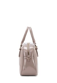 Borsa a mano in vernice rosa chiaro con forma rettangolare, doppi manici, zip dorata e un accento in metallo a forma di anello. Texture liscia.