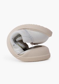 Scarpa in pelle bianca con suola in gomma beige, caratterizzata da una forma arrotondata, texture morbida e imbottitura interna. La scarpa è parzialmente ripiegata.