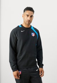 Sort sweatshirt med blå detaljer, prydet med et logo og et emblem. Fremstillet af blødt stof med rund hals og lange ærmer.