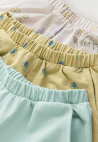 Kolm paari lühikesi pükse: üks valget värvi lillemustriga, üks kollane väikeste siniste lilledega, ja üks ühtlane mentroheline, kõik kummikummiga vöökohaga.