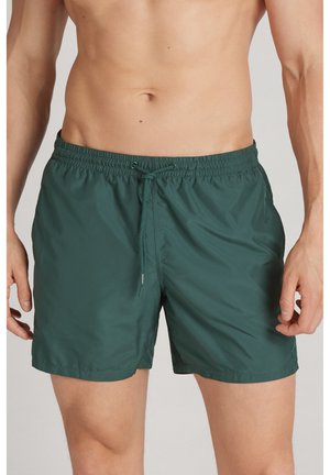 Bañador verde hecho de tela ligera y suave. Cuenta con una cintura elástica con cordón y bolsillos laterales.