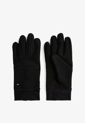 Czarne rękawiczki wykonane z miękkiego, elastycznego materiału. Charakteryzują się eleganckim wzornictwem, pięcioma palcami oraz teksturowanym uchwytem z małym logo w obszarze nadgarstka.