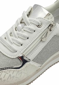 Weiße Sneakers mit einer Mischung aus glatten und strukturierten Materialien, silbernen Akzenten, einem metallischen Reißverschluss und einer flachen Gummisohle.