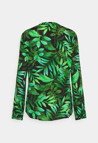 Långärmad skjorta med svart bakgrund och stora gröna bladmönster, tillverkad av lätt tyg med en mjuk textur.