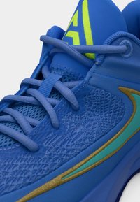 Μπλε αθλητικό παπούτσι με διχτυωτό επάνω μέρος, μπλε κορδόνια, τιρκουάζ και χρυσό λογότυπο Nike swoosh και κίτρινο-πράσινο λογότυπο στη γλώσσα.