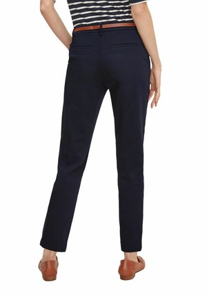Marineblaue Hosen im Slim Fit mit glatter Textur, zwei hinteren Taschen und einem braunen Ledergürtel. Entworfen mit einem klaren, maßgeschneiderten Look.