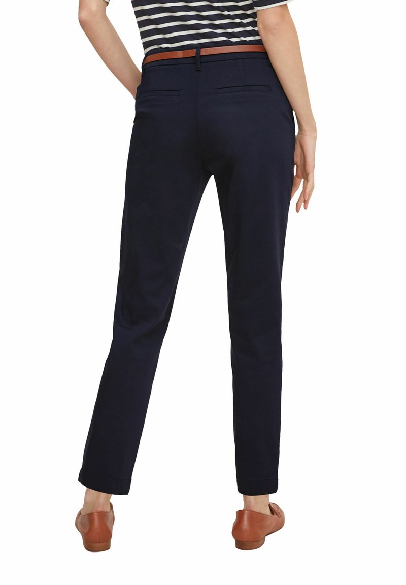 Pantaloni blu navy dal taglio slim, caratterizzati da una texture morbida, due tasche posteriori e una cintura in pelle marrone. Progettati con un aspetto pulito e su misura.