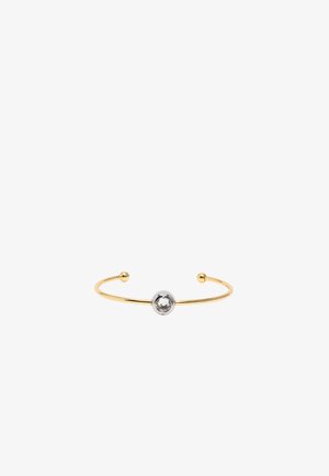 Brazalete de puño en tono dorado con una perla central en tono plateado que presenta una gema clara. Diseño abierto con extremos redondeados.