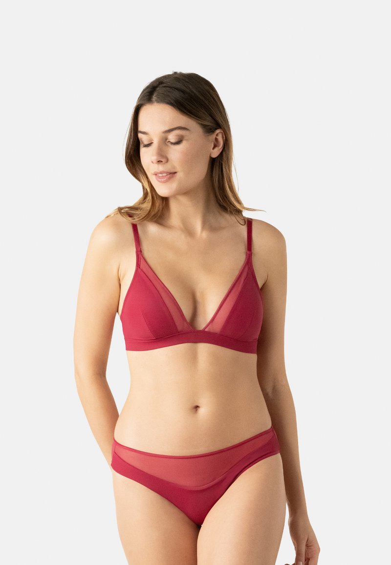 Ensemble soutien-gorge rouge et culotte assortie en tissu doux, avec un décolleté en V profond, des détails transparents et des bretelles réglables pour un confort optimal.