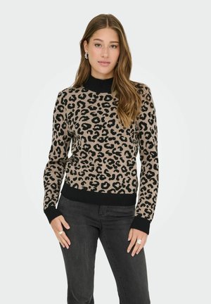 Pull en imprimé léopard beige et noir en tricot avec un col roulé noir à côtes et des poignets. Associé à un pantalon noir avec une texture lisse.