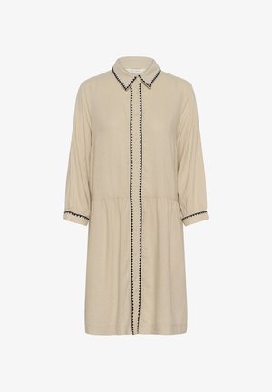 Beige knielange jurk met lange mouwen, knoopsluiting aan de voorkant, puntige kraag en zwarte zigzagbies op de kraag, knopenlijn en manchetten.