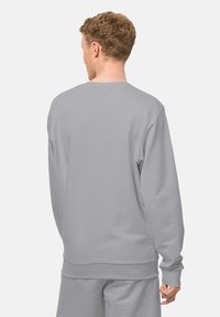 Felpa grigia chiara con scollatura a girocollo, polsini e vita a costine. Tessuto morbido; design semplice senza loghi o motivi visibili.