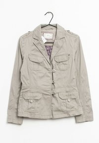 Giacca beige chiaro con colletto, tasche frontali e chiusura a bottoni. Realizzata in tessuto morbido con una fodera interna a fantasia.
