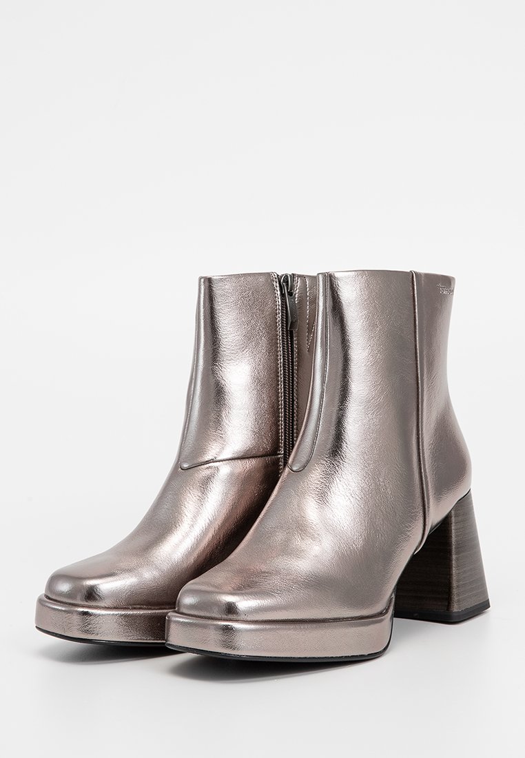 Bottes chelsea argentées métalliques avec une finition en cuir lisse, dotées d'une fermeture éclair sur le côté et d'un large talon en bois pour la stabilité.