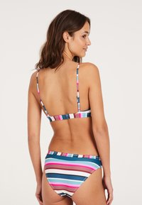 Juostuotas bikinis, kuriame dominuoja pastelinių rožinės, mėlynos ir rudos spalvų derinys. Viršus turi plonas reguliuojamas petnešas, o apatinė dalis pasižymi žemu kirpimu ir lygiu paviršiumi.