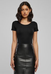 Body nero a maniche corte abbinato a una gonna a matita nera in pelle a vita alta. Tessuto liscio con design aderente e scollo rotondo.