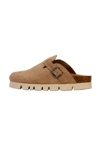 Chaussure à sabot en daim beige avec une boucle sur le côté, semelle de plate-forme texturée et accent en liège au talon. Vue latérale mettant en avant la forme et le design.