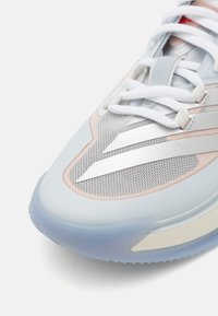 Light blue athletic shoe featuring a mesh upper, silver metallic accents, white laces, and a translucent sole with textured grip.