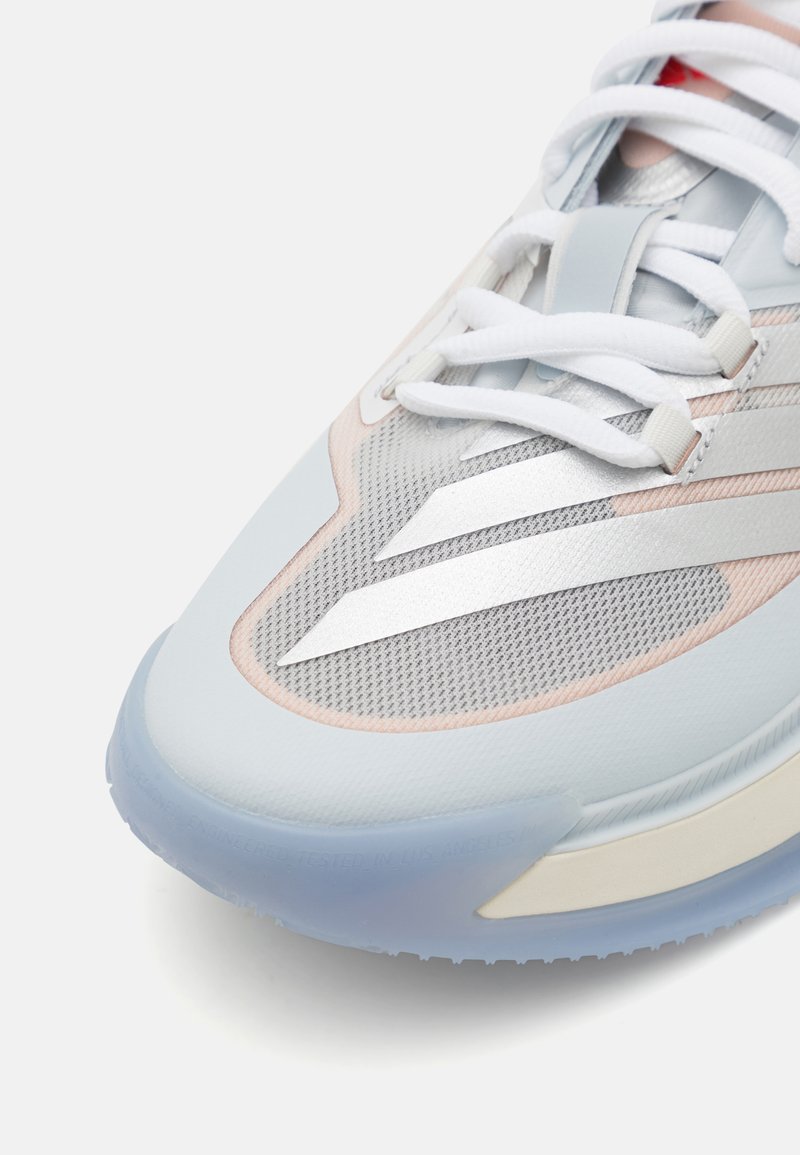 Chaussure de sport bleu clair avec une tige en maille, des accents métalliques argentés, des lacets blancs et une semelle translucide avec un grip texturé.