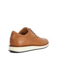 Men's brown leather shoe with textured surface, round toe, and a white rubber sole with a navy edge. Black laces and subtle branding detail.