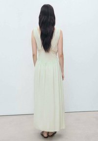 Long cream dress with a fitted bodice, lace detailing at the back, and a flowy skirt. The fabric appears lightweight and smooth.