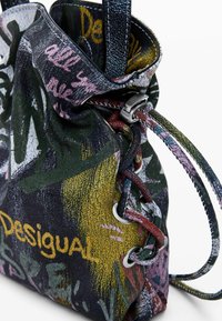 Viacfarebný taška so šnúrkou vyrobená z textúrovaného materiálu, s grafitovými vzormi v zelenej, žltej, ružovej a strieborných akcentoch.