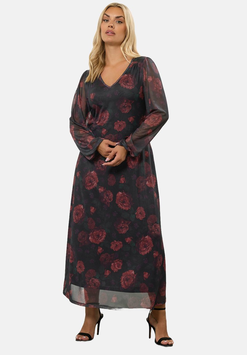 Vestido maxi de tela transparente con base negra y gran patrón floral rojo. Presenta un escote en V y mangas largas y fluidas.