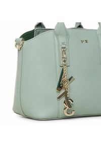 Borsa a tracolla in ecopelle verde menta con design strutturato, dettagli in metallo dorato e un ciondolo con il numero 73 attaccato a una cerniera laterale.